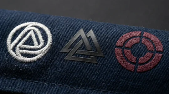 Gros plan sur différentes textures de marquages textiles professionnels montrant les reliefs et finitions de broderie, flocage et sérigraphie sur tissus techniques pour vêtements de travail