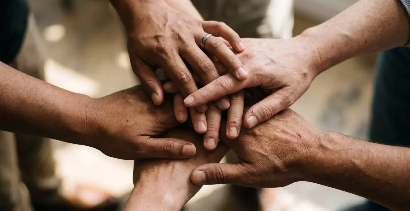 Mains de collaborateurs divers se rejoignant symboliquement dans un geste de cohesion d'equipe